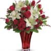 Red and white rose floral arrangement in red glass vase