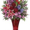 Pink lily and red rose flower arrangement in red glass vase