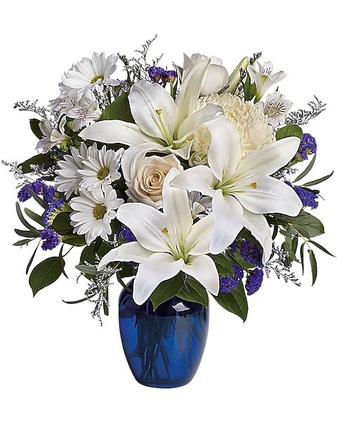 White lily and rose floral arrangement in blue glass vase