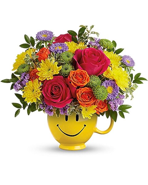 Yellow and red roses mixed with bright flowers in a yellow smiley mug from Gurnee florist