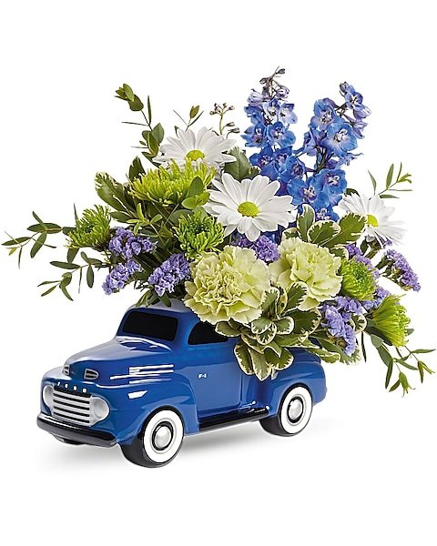 Yellow and white rose arrangement in blue pickup truck planter