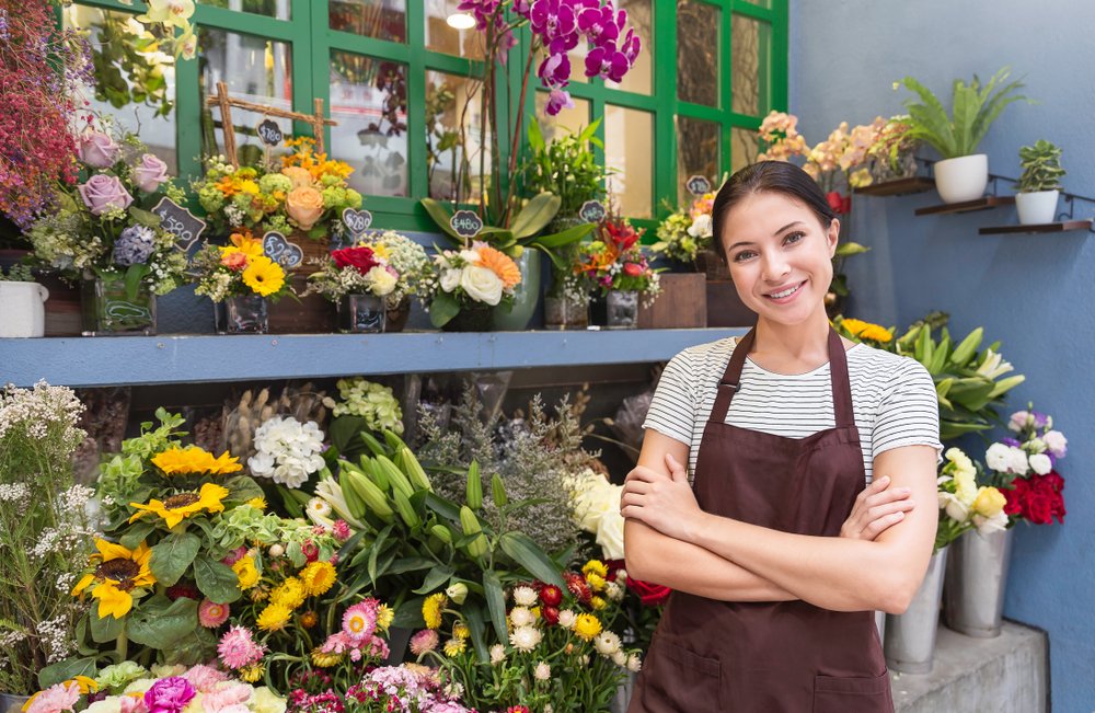 Smiling florist standing in front of floral displays at our Gurnee florist shop.